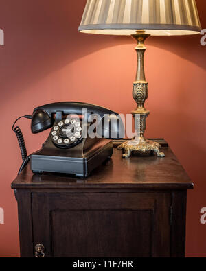 'Old telephone and lamp on bedside table in The Zetter Townhouse in London, England' Stock Photo