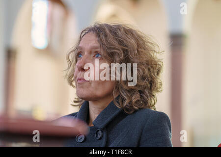 Devout religious middle-aged woman praying in a church kneeling alone in a pew looking up to the altar with a sincere spiritual expression in a low an Stock Photo