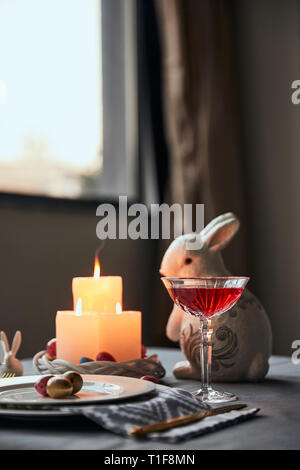selective focus of plates with eggs, wine in crystal glass and decorative rabbit  on table at home Stock Photo
