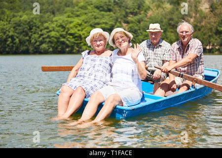 Active seniors group takes a boat trip in rowing boat in the summer on the lake Stock Photo