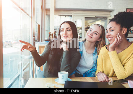 These girls are gossiping Just sitting at the table in cafe and speaking about another man. Young women are amazed and trying to tell one another Stock Photo