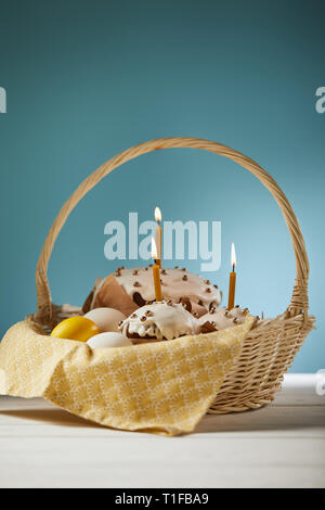 Easter cakes with chicken eggs and napkin in wicker basket on turquoise Stock Photo