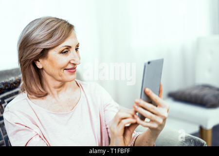 Beautiful middle aged woman in casual clothes is making selfie Stock Photo
