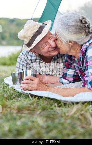 Senior couple gives a kiss in the tent at the campsite during summer vacation Stock Photo