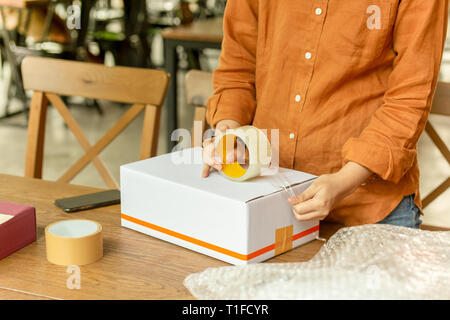 Startup small business woman owner packing cardboard box at workplace. Stock Photo