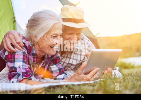 Couple of seniors at videochat using tablet computer while camping in summer Stock Photo