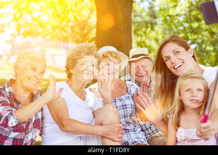 Extended family with grandparents and child using selfie stick while taking pictures Stock Photo