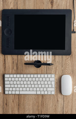 top view of graphic tablet, graphic pen, wireless computer keyboard and computer mouse on wooden table Stock Photo