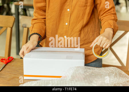 Startup small business woman owner packing cardboard box at workplace. Stock Photo