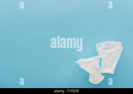 top view of white, crumpled plastic cups on blue background with copy space Stock Photo