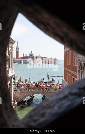 Last view of Venice from Bridge of Sighs as seen by prisoners going to the dungeons with tourists on Ponte della Paglia and a view to San Giorgio Magg Stock Photo