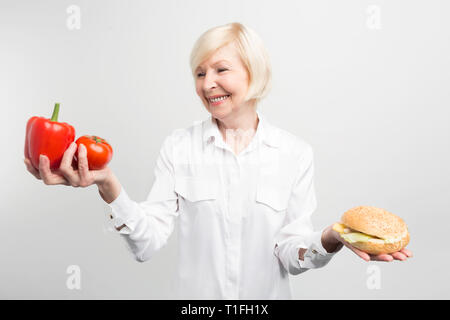 A picture of dilemma between good and bad meal. What is better to choose: two good peppers or one tasty burger .The answer is obvious but not easy to Stock Photo