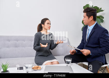 Attentive psychologist. Attentive psychologist holding pencil in his hands making written notes while listening to his client Stock Photo