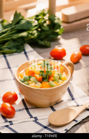 Ladle of steamed freshly harvested young vegetables including crinkle cut sliced carrots, peas and potato for a healthy accompaniment to dinner Stock Photo