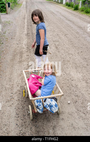 Girl pulling her younger sister in a red wagon Stock Photo - Alamy