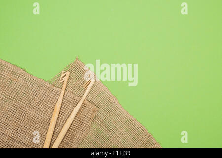 bamboo toothbrushes and brown sackcloth on light green background Stock Photo