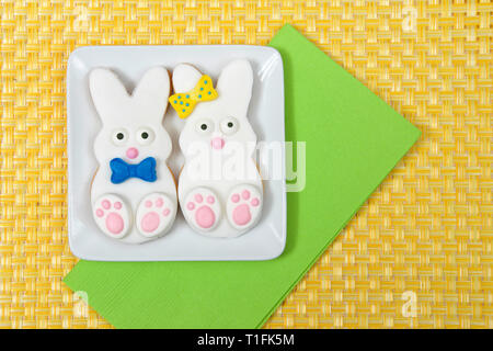 Easter Bunny Sugar Cookies on a plate with yellow place mat background. Marshmallow fondant covered cookie with candy feet, eyes and nose and tail and Stock Photo