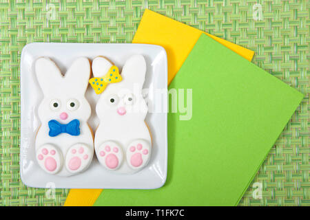 Easter Bunny Sugar Cookies on a plate with green place mat background. Marshmallow fondant covered cookie with candy feet, eyes and nose and tail and  Stock Photo
