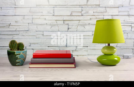 White wooden desk with a few books, a modern table lamp and a small cactus Stock Photo