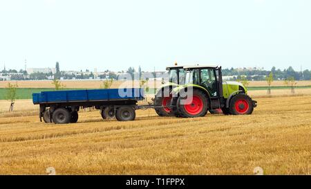 2 tractor pullers with flatbed trailers standing in harvested field stubble Stock Photo