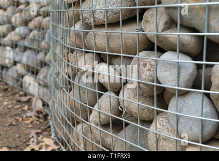 rounded stones behind metal mesh Stock Photo