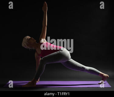 Yoga instructor practicing a low lunge pose on a yoga mat ...