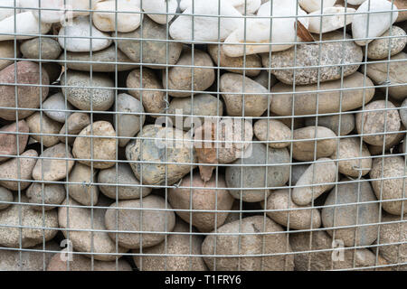 rounded stones behind metal mesh Stock Photo