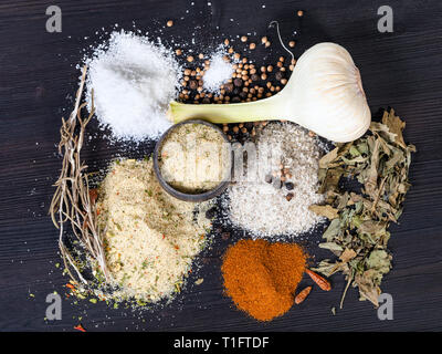 top view of various Seasoned Salts with ingredients on dark brown wooden board Stock Photo