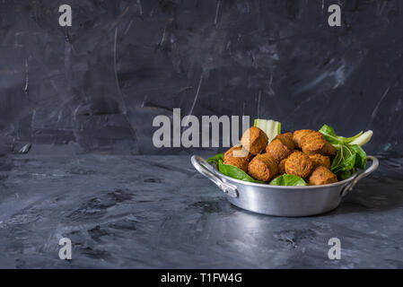 falafel balls served in plate with green leafs on wooden black background Stock Photo