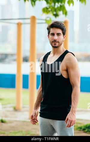 Beautiful young man training and working out in park. Handsome hispanic athlete standing and looking at camera after fitness routine. Portrait of Lati Stock Photo