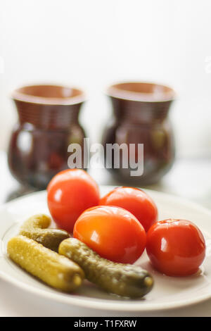 pickled cucumbers and tomatoes on a table with two cups Stock Photo