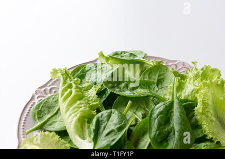 A mixture of spinach leaves and salana leaves on a plate. Selective focus, white background Stock Photo