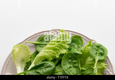 A mixture of spinach leaves and salana leaves on a plate. Selective focus, white background Stock Photo