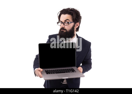 Frowning bearded businessman with a laptop in hand, raising an eyebrow looking at the camera, isolated on white background Stock Photo