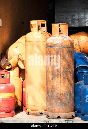 Different color and size cylinder gas bottles stored in a delivery van for refill and supply Stock Photo