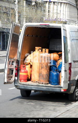 Different color and size cylinder gas bottles stored in a delivery van trunk for refill and supply Stock Photo