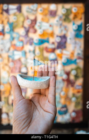 Man's hand holds a toy sailboat with a blue flag Stock Photo