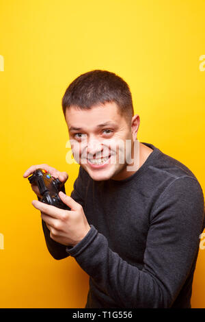 Image of man with joystick in his hands on empty orange background. Stock Photo