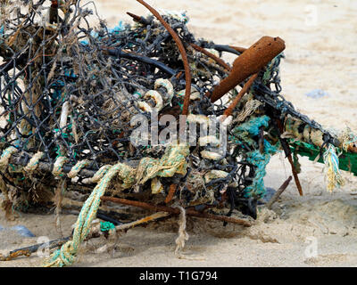 The battered remains of a crab or lobster pot on a Norfolk beach poses a danger to marine life (seals and fish) from plastics and netting Stock Photo