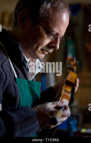 Andrew Hutchinson, a violin maker and restorer, repairing an instrument using a chisel in the workshop of his premises at Hoylake, Wirral, north west England. Mr Hutchinson trained at Newark School of Violin Making and established The Violin Shop in 1982. Stock Photo