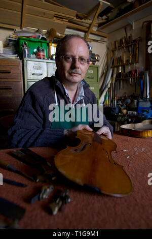 Andrew Hutchinson, a violin maker and restorer, examining a damaged instrument in the workshop of his premises at Hoylake, Wirral, north west England. Mr Hutchinson trained at Newark School of Violin Making and established The Violin Shop in 1982. Stock Photo