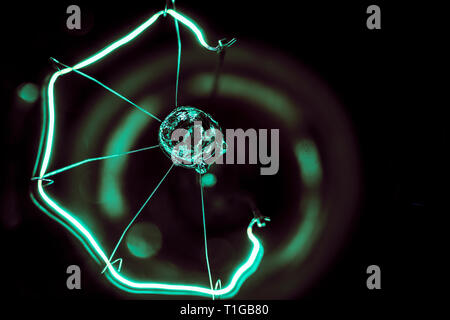 A  macro photography of an old fashion glass light bulb in greenish hue in black background Stock Photo