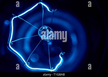 A  macro photography of an old fashion glass light bulb in blueish hue in black background Stock Photo