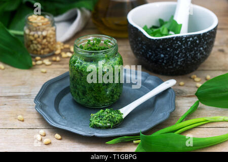 Ramson pesto and ingredients for cooking it on a wooden table. Rustic style. Stock Photo