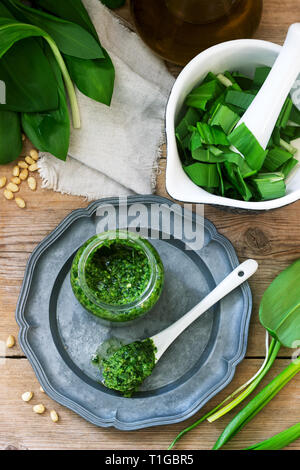 Ramson pesto and ingredients for cooking it on a wooden table. Rustic style. Stock Photo