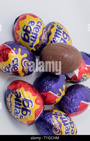 London, UK - March 2019: Cadbury creme egg in different sizes in a colorful wrapper showing an unwrapped chocolate with white and yellow inner filling Stock Photo