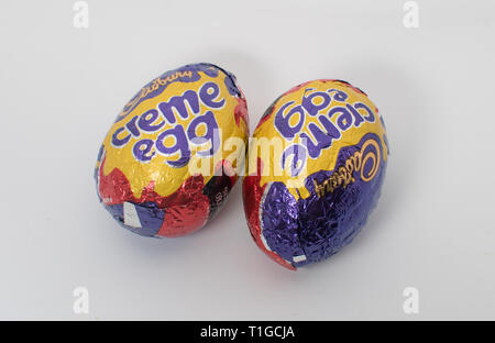 London, UK - March 2019: Cadbury creme egg in different sizes in a colorful wrapper showing an unwrapped chocolate with white and yellow inner filling Stock Photo