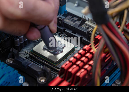 Engineer applying thermal paste on the computer board chip cpu Stock Photo