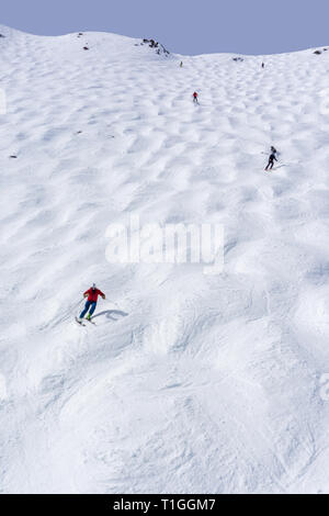 Skiers descending the steep mogul ski hill slope at a mountain in Lake Louise in the Canadian Rockies of Alberta, Canada. Stock Photo