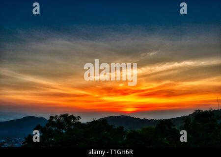 This unique image shows the beautiful red sunset with great cloud formation behind the mountains in Hua Hin in Thailand Stock Photo